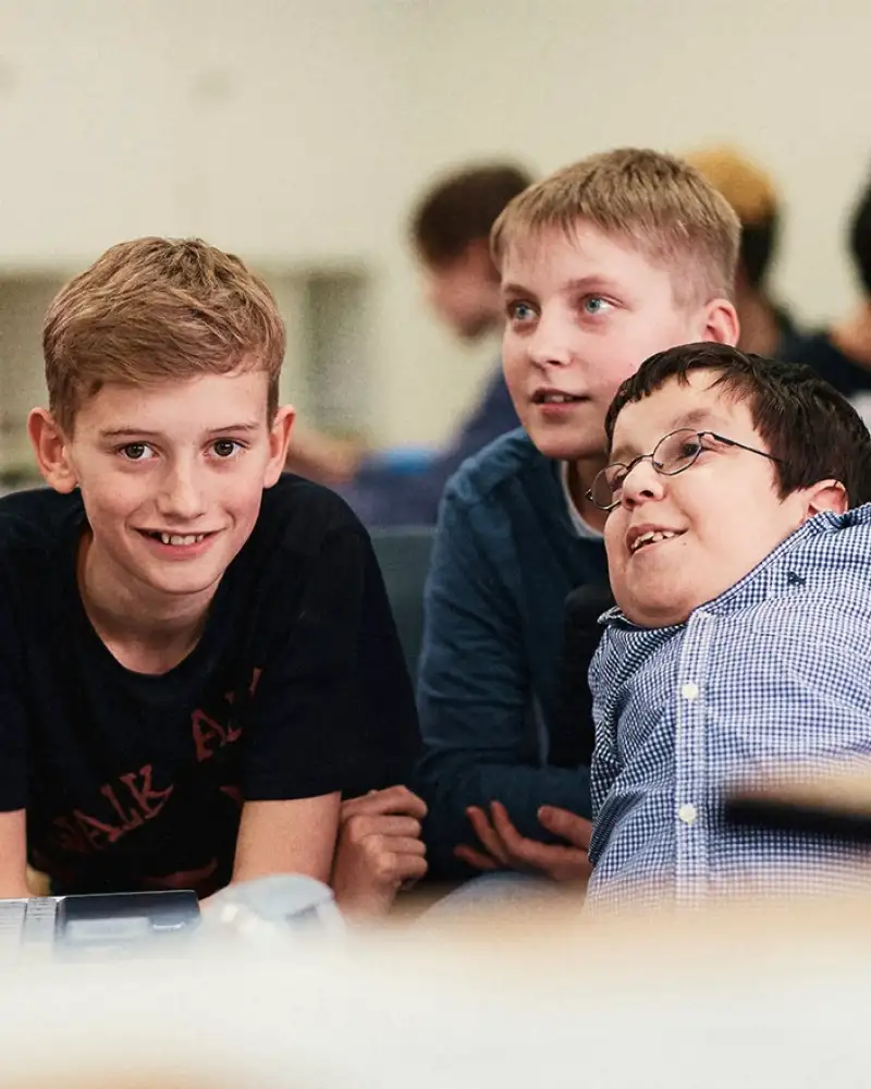 Drei Jungen, einer von ihnen hat eine Körperbehinderung