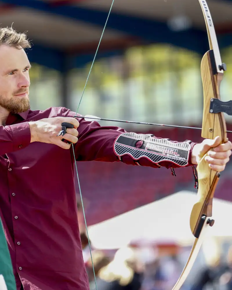Ein junger Mann spannt einen Bogen.