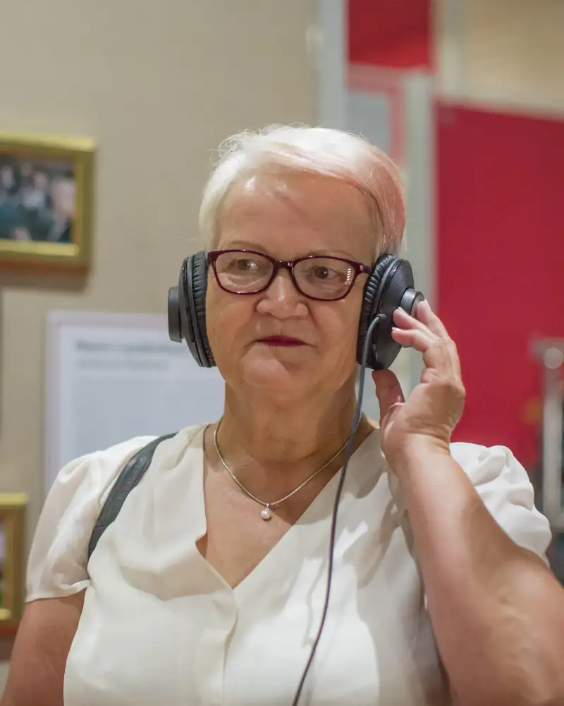 Eine Frau hat Kopfhörer auf und hört konzentriert zu.