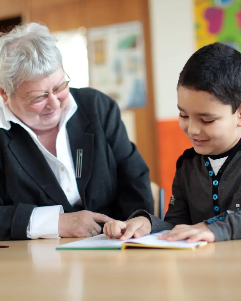 Eine Frau und ein kleiner Junge schauen auf ein aufgeschlagenes Buch. Der Junge liest daraus vor.