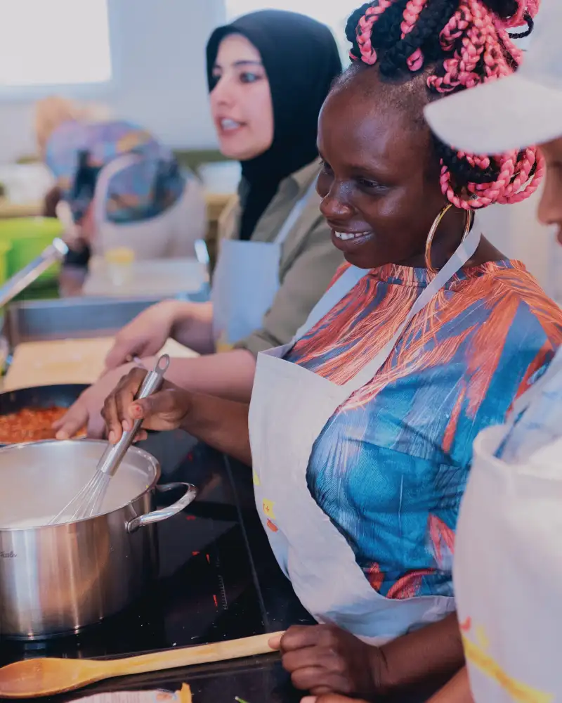 Drei Frauen mit Migrationshintergrund bereiten in einer Küche gemeinsam Speisen zu.