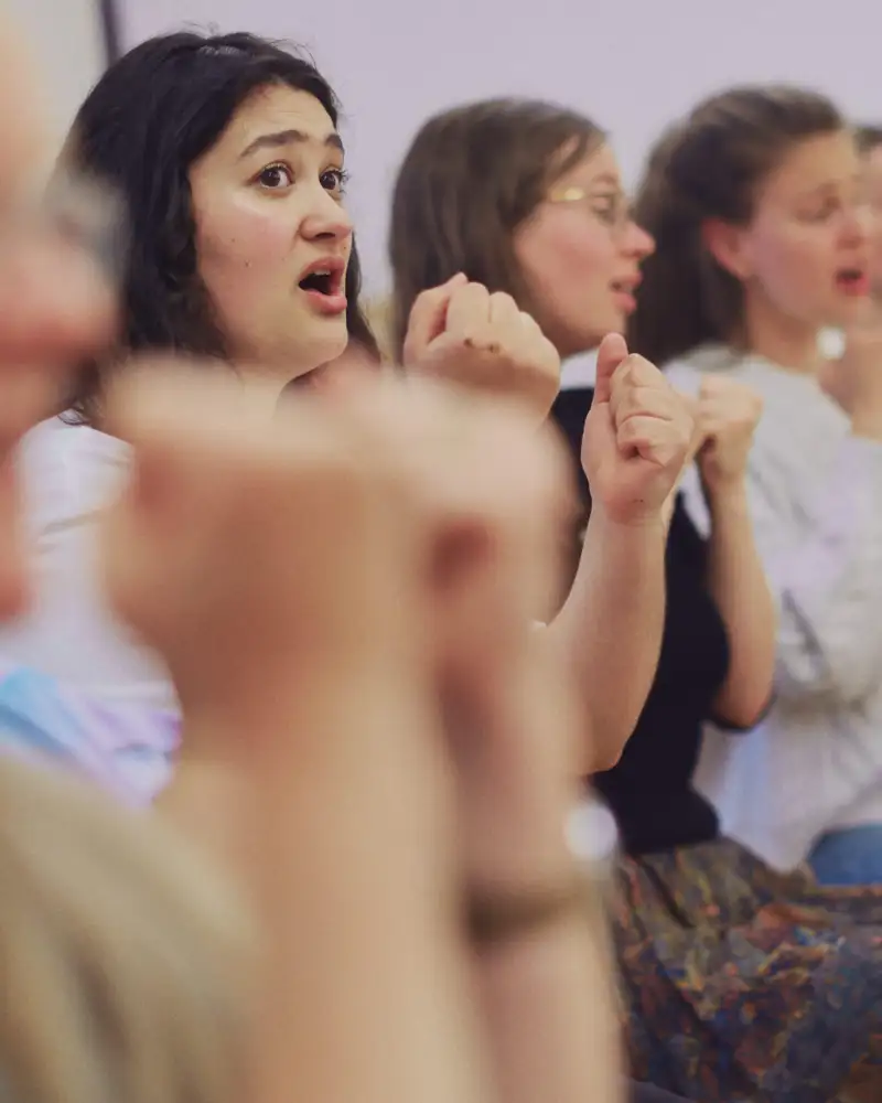 Drei Mädchen stehen in einer Reihe und singen.