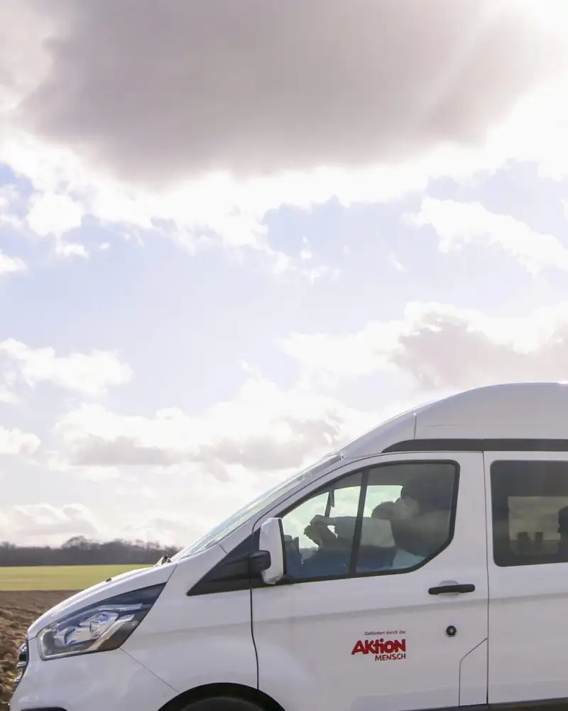 Ein weißer Ford Transit fährt durch eine flache Landschaft.
