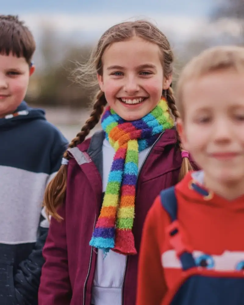 Drei Kinder stehn nebeneinander im Grünen
