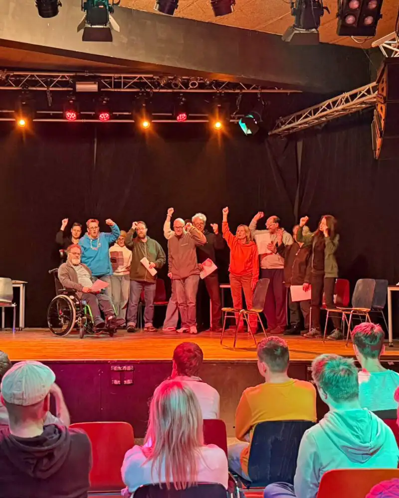 Eine Gruppe von Menschen auf einer Theaterbühne vor Publikum