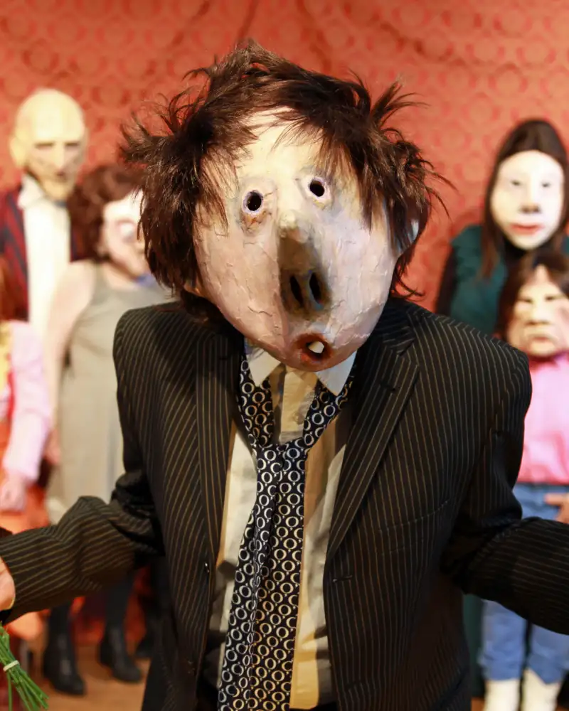 Eine Person mit phantasievoller Maske, im Hintergrund weitere Personen mit Masken