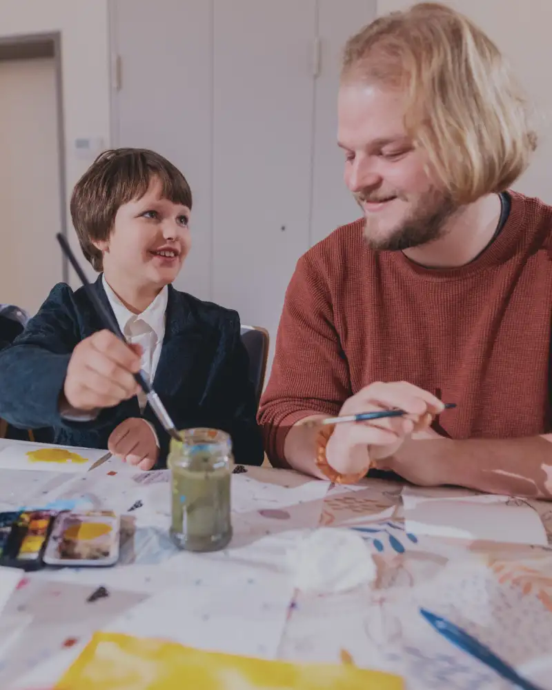 Ein Junge und ein junger Mann sitzen zusammen und Malen.