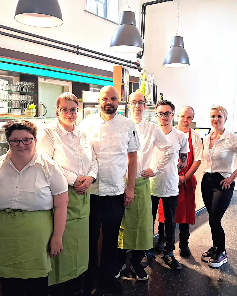 Teamfoto von Mitarbeiter*innen in einem Bistro