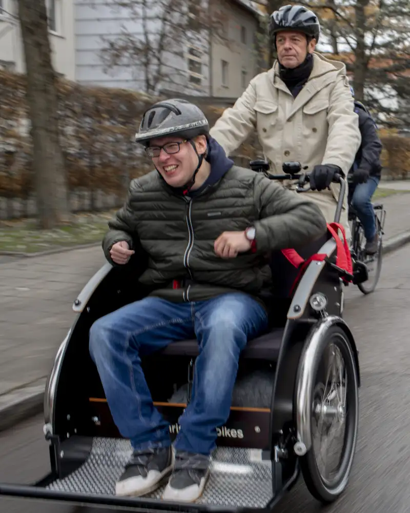 Ein Fahrer unterwegs auf einer Straße mit einem Passagier in einer Fahrradrikscha
