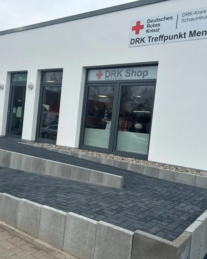 Ein flaches Gebäude mit einem großen Schild, auf dem steht: DRK Treffpunkt Mensch. Zum Eingang füht eine lange Rampe
aus Beton.