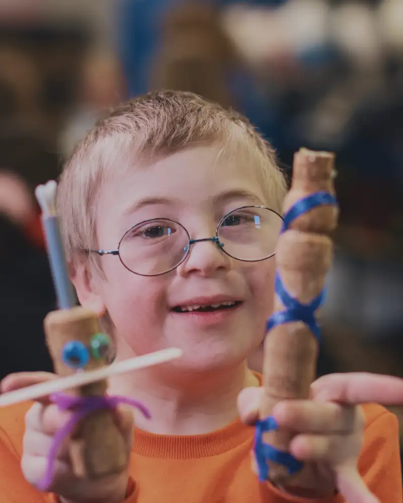 Ein Junge mit Downsyndrom zeigt selbstgebastelte Figuren