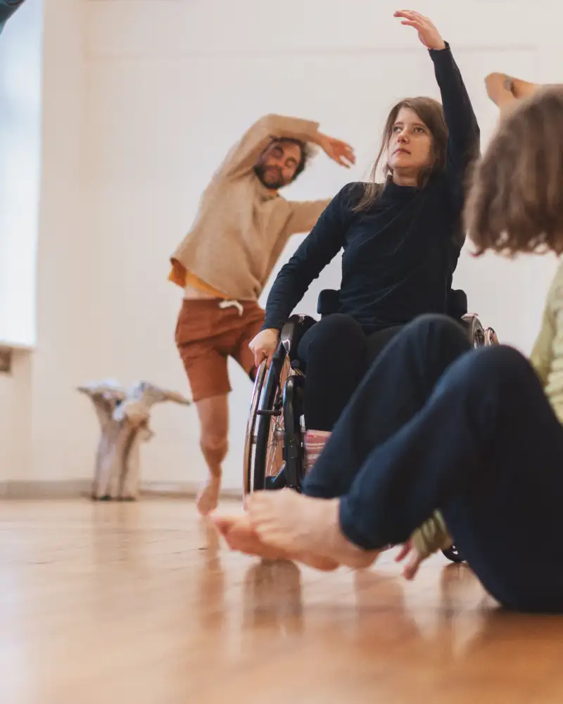 Verschiedene Personen, darunter eine Frau im Rollstuhl, bei einer Tanzimprovisation