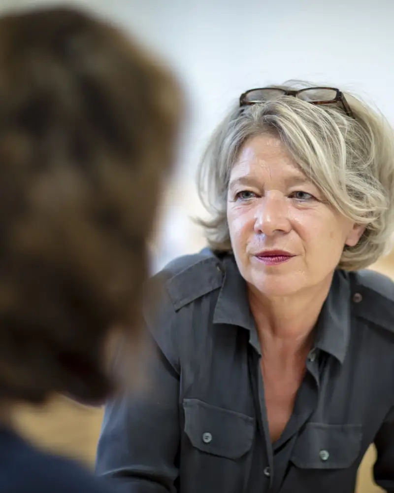 Eine Frau sitzt einer anderen Person gegenüber und hört ihr zu.