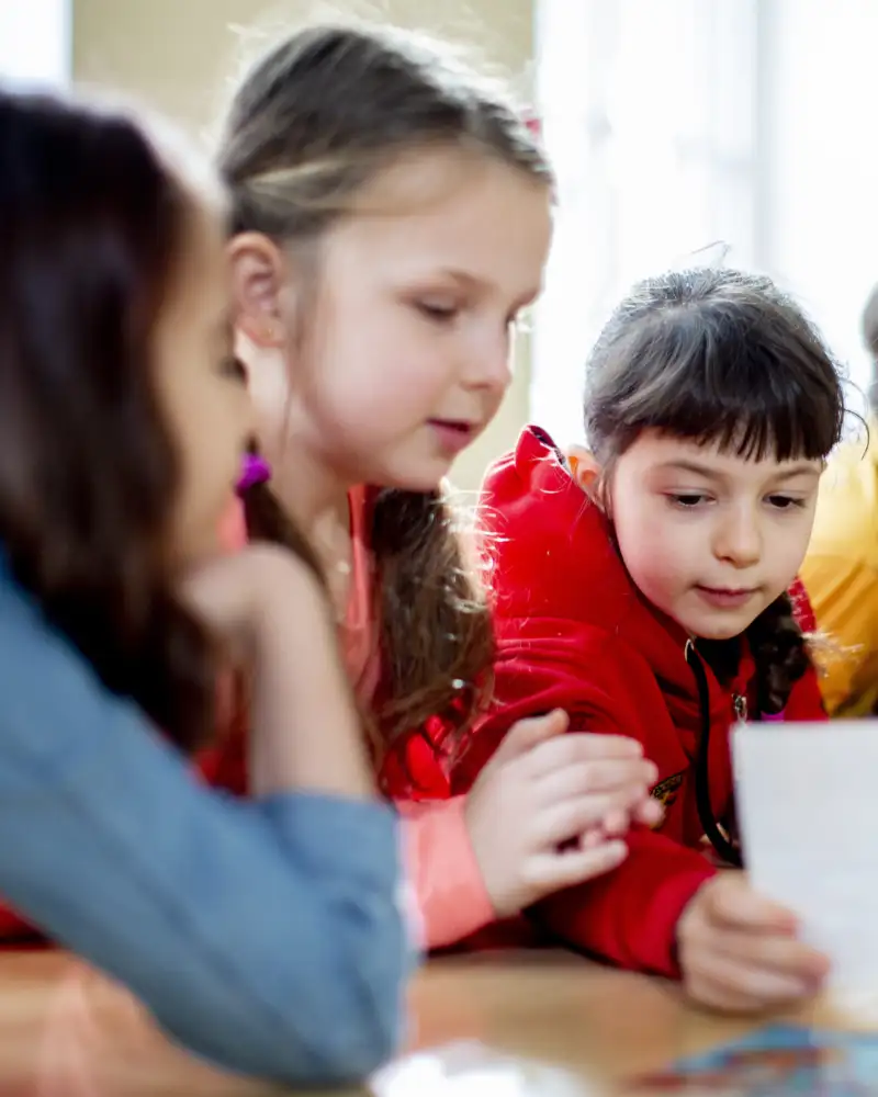 Mehrere Kinder im Grunschulalter schauen an einem Tisch auf ein Papier