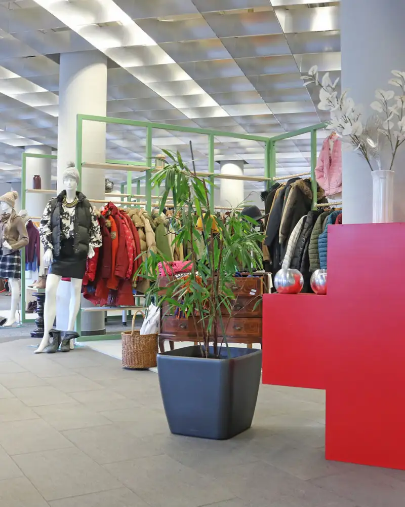 Blick in ein Kaufhaus mit Kleidung, im Vordergrund ein großes Rotes Kreuz