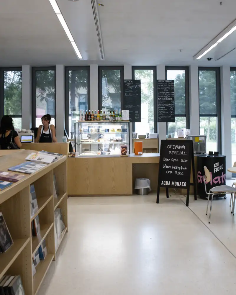 Blick in ein Café. Links im Bild ist ein Regal mit ausgelegten Broschüren zu sehen
