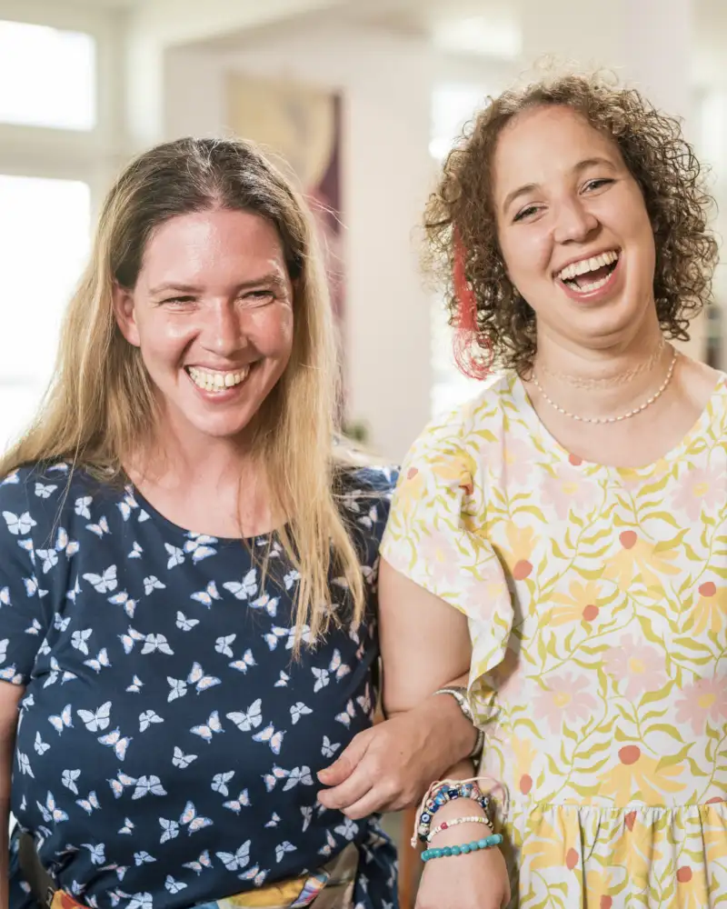 Zwei junge Frauen stehen lachend nebeneinander