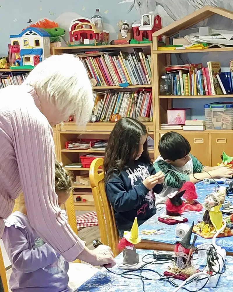 Eine Gruppe Kinder und eine Frau an einem Basteltisch