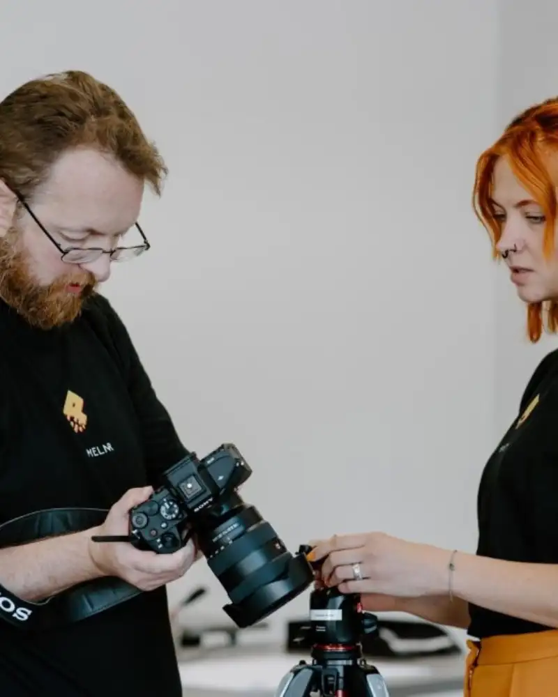 Ein Mann mit Spiegelreflexkamera steht neben einer Frau mit einem Fotostativ.