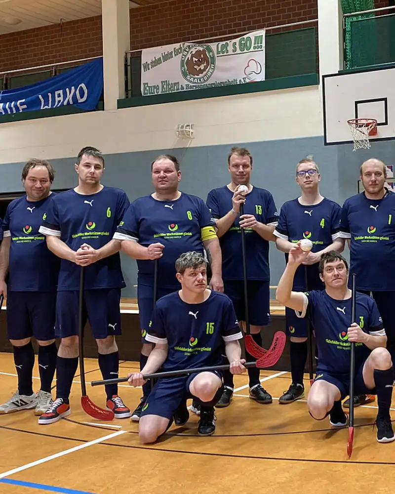 Gruppenfoto einer Männer-Sportmannschaft in einer Sporthalle