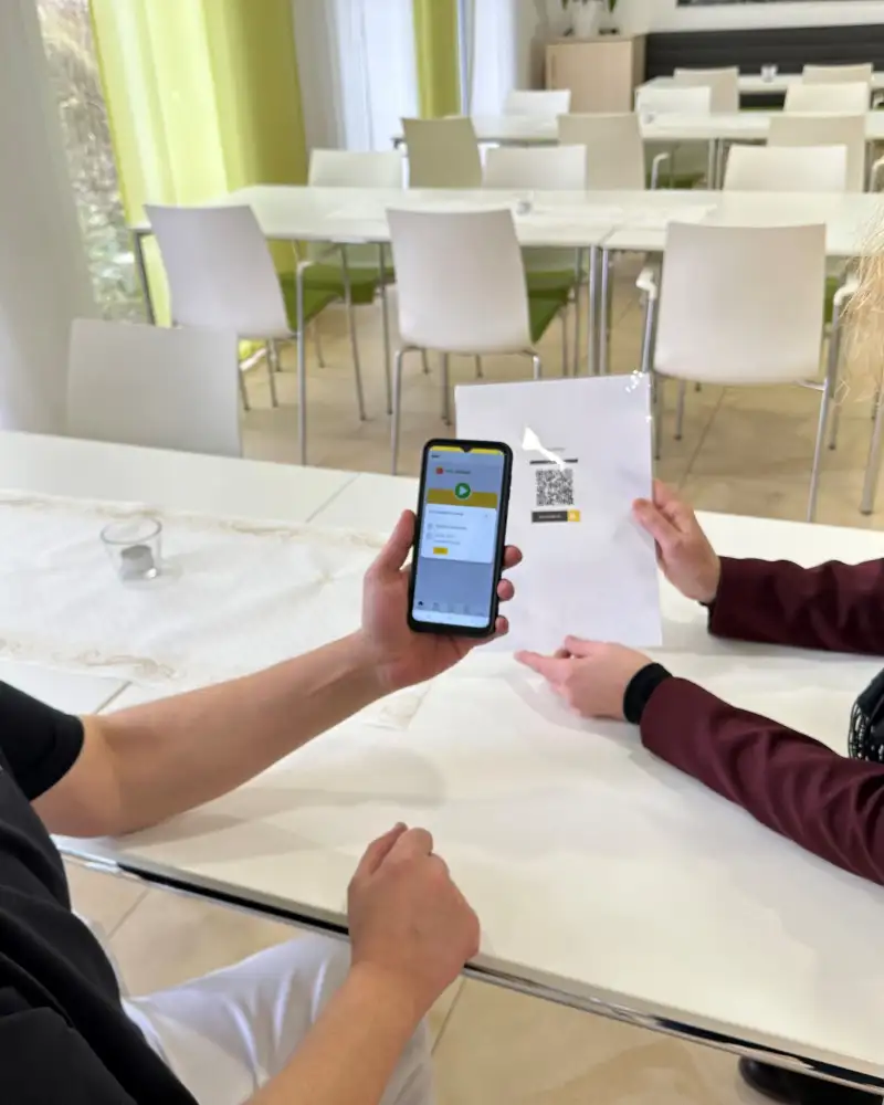 Ein Mann und eine Frau schauen auf den Bildschirm eines Smartphones, das der Mann in der Hand hält.