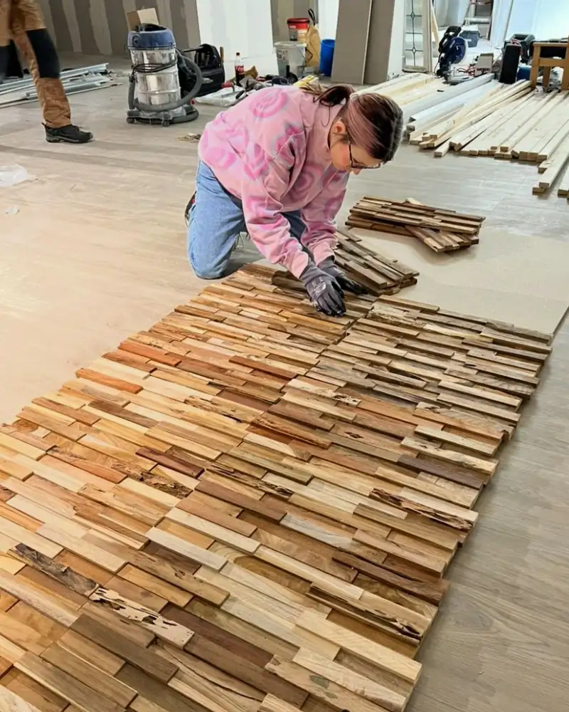 Eine junge Frau arbeitet am Boden eines Raums mit Holz