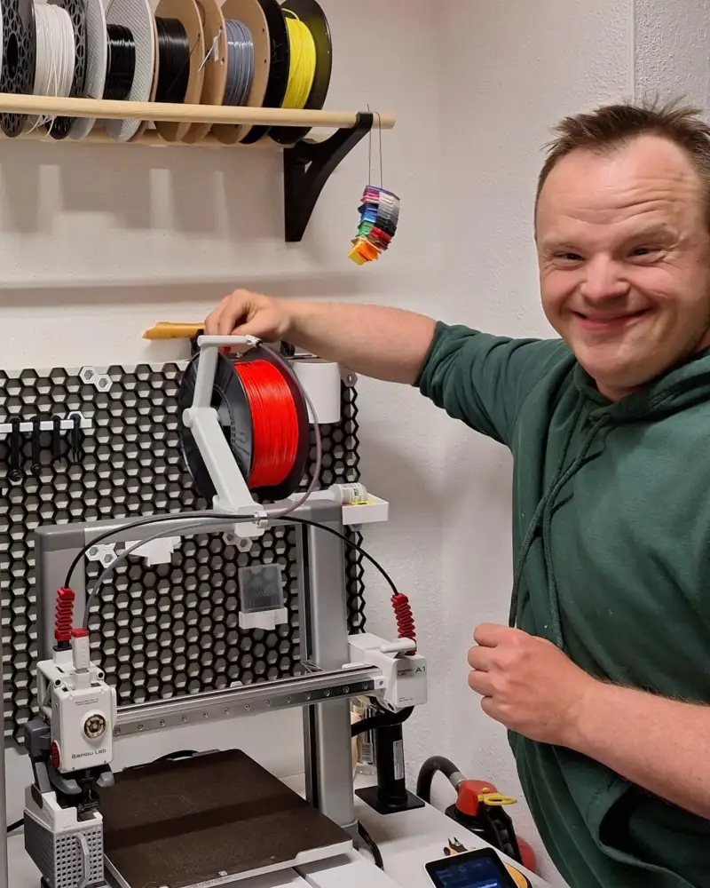 Ein Mann mit Downsyndrom bedient einen 3D-Drucker.