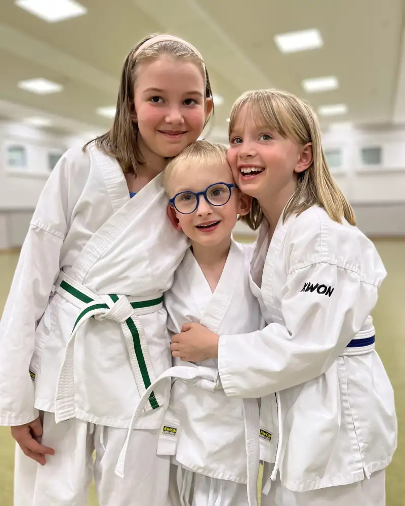 Zwei Mädchen und ein Junge in Karate-Kleidung.