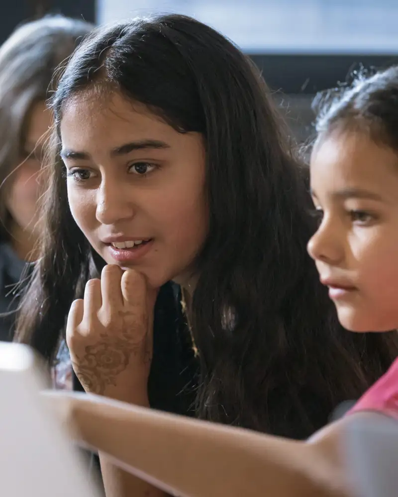 Ein junges Mädchen und ein Kind schauen auf einen Bildschirm