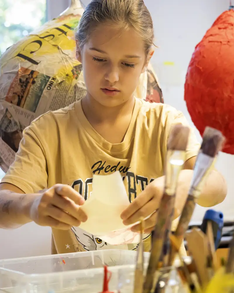 Ein Mädchen an einem Tisch mit vielen Bastelsachen