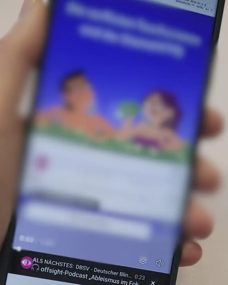 Eine Hand hält ein Smartphone, das Display ist nur unscharf zu sehen.