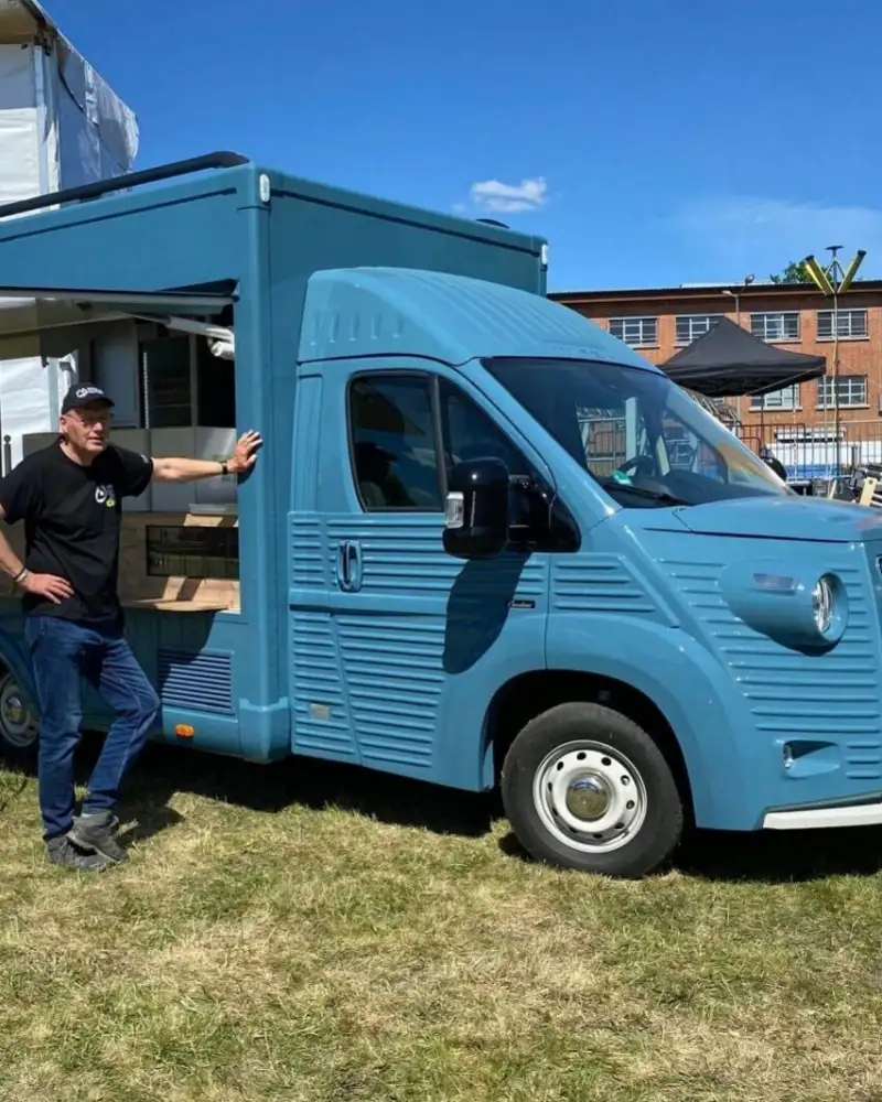 Ein Mann steht vor einem blauen Foodtruck