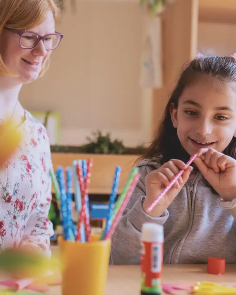Eine junge Frau mit Downsyndrom und ein Mädchen basteln