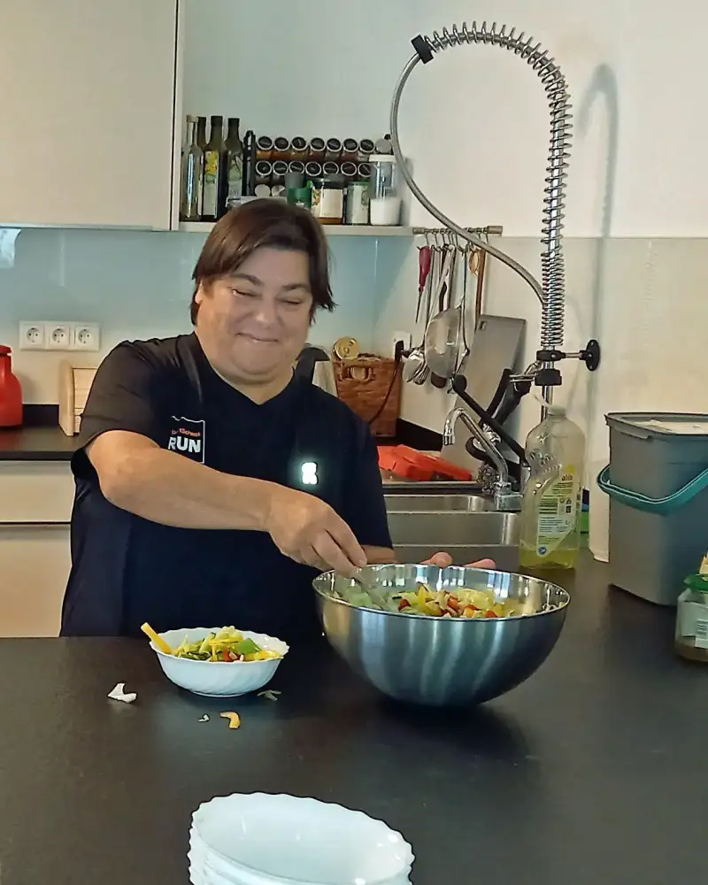 Eine Frau bereitet in einer Küche einen Salat zu.