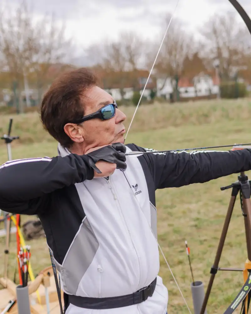 Eine Frau mit Sonnenbrille beim Bogenschießen