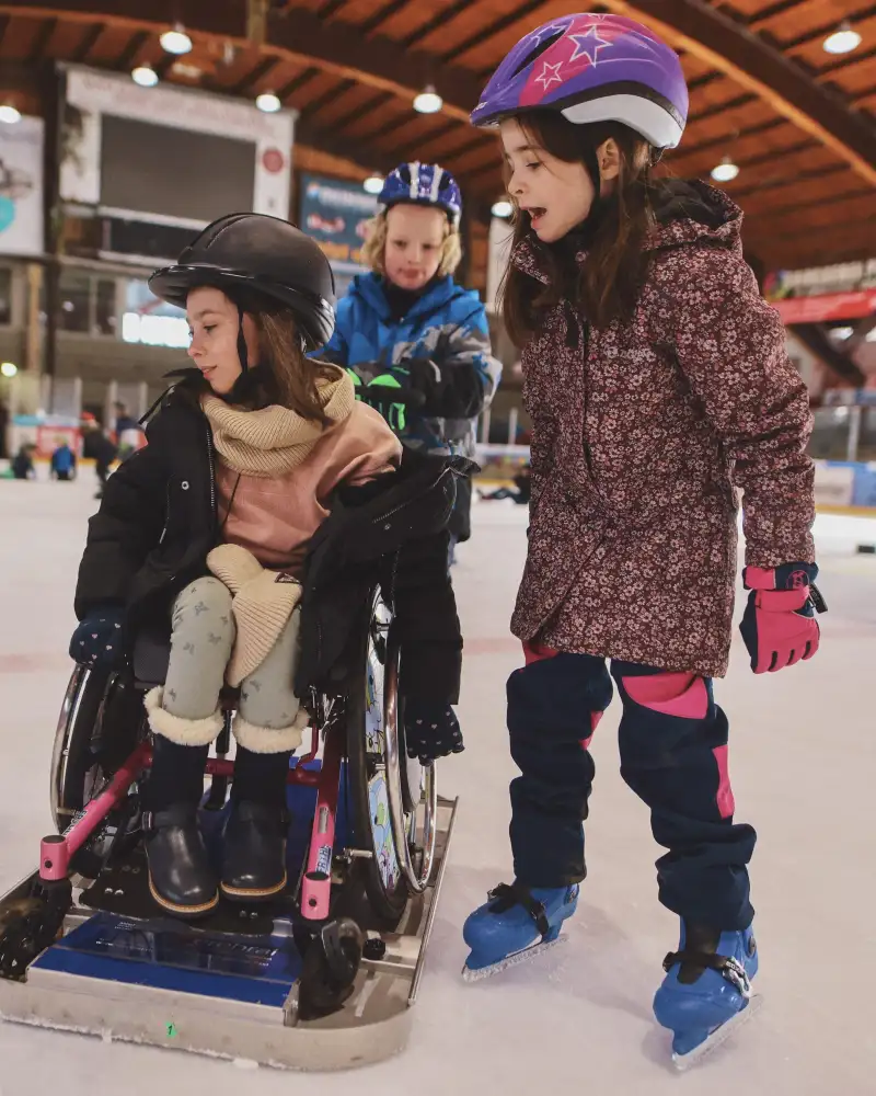 Kinder in der Eishalle, eines davon im Rollstuhl