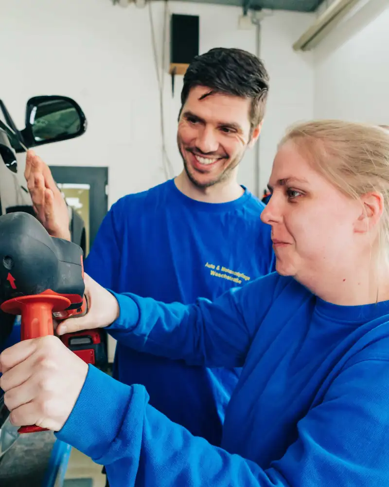 Eine Frau und ein Mann arbeiten an einem Auto
