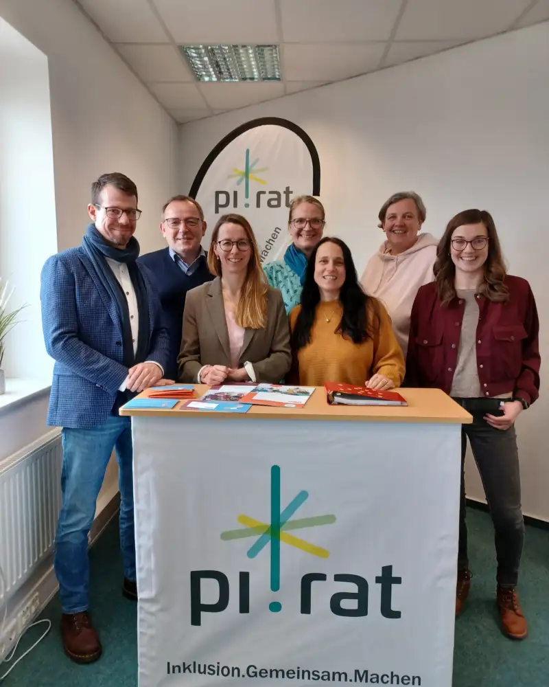 Sieben Personen stehen hinter einem Pult, auf dem steht: pi!rat