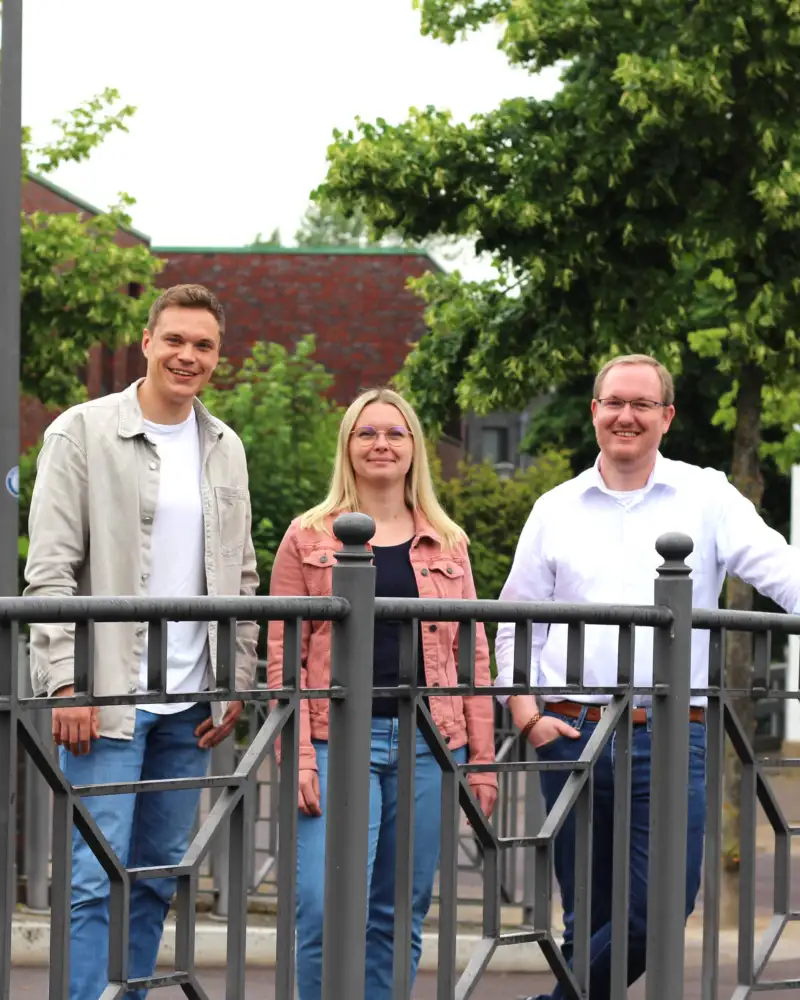 Zwei Männer und eine Frau stehen auf einer Brücke.