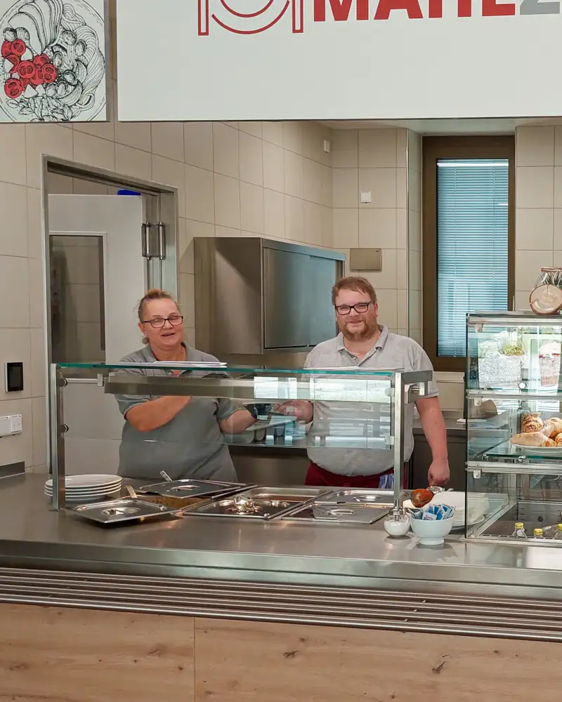 Drei Personen stehen hinter der Theke des Bistros Mahlzeit