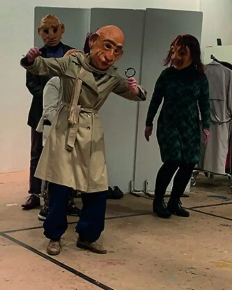 Mehrere Personen mit grußen Masken beim Theaterspiel