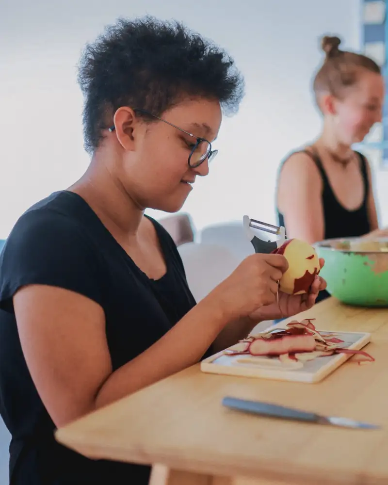 Zwei junge Frauen sitzen an einem Tisch und bereiten Essen vor