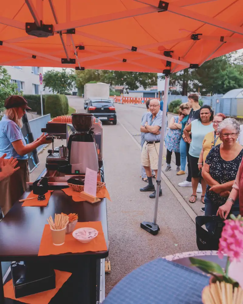 Menschen stehen an einem überdachten mobilen Kaffeestand.