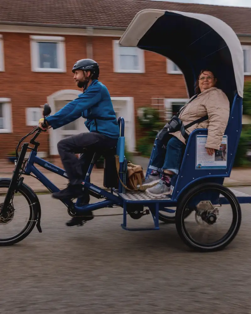 Zwei Personen fahren mit einer E-Rikscha