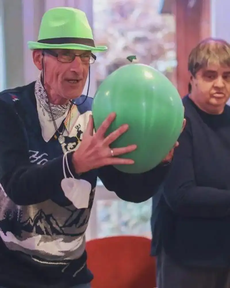 Ein Mann mit grünem Hut und grünem Ball umringt von anderen Menschen