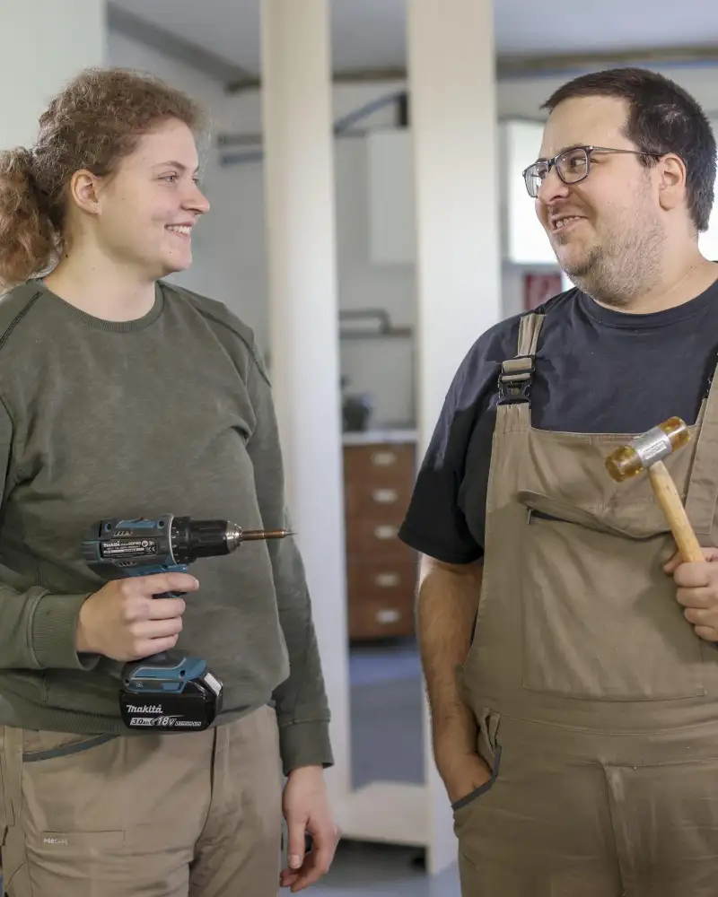 Eine Handwerkerin und ein Handwerker stehen nebeneinander