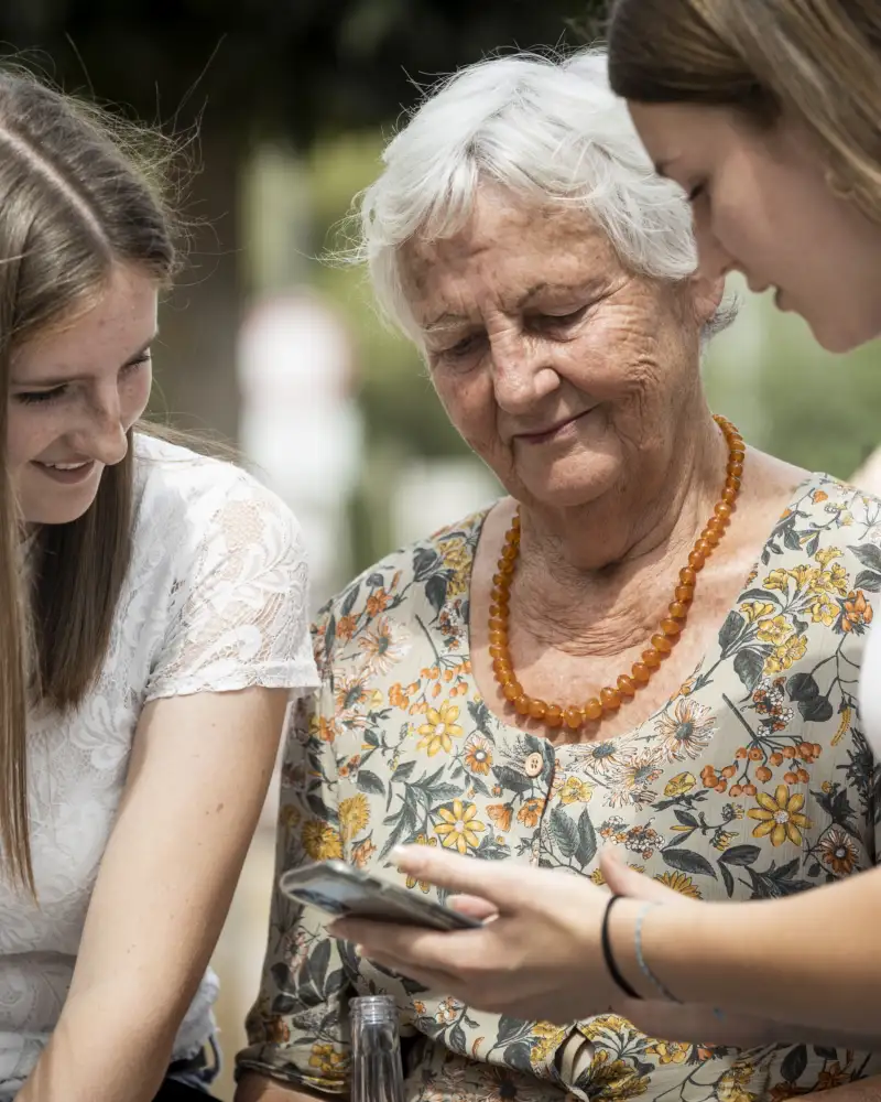 Zwei jüngere und eine ältere Frau schauen auf ein Smartphone