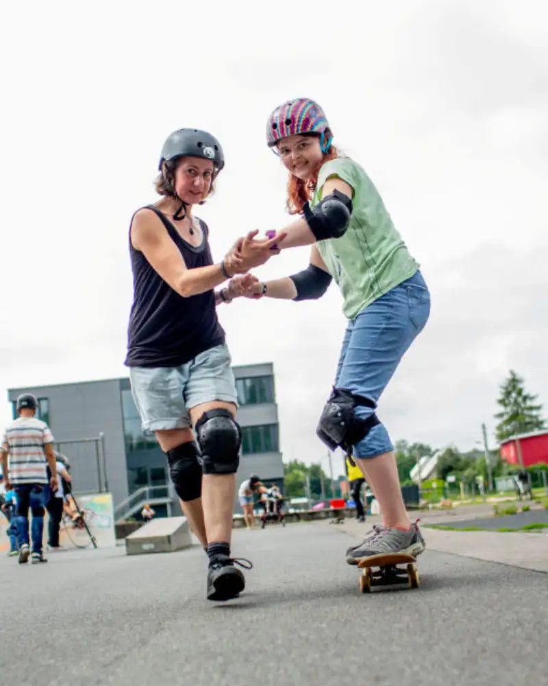 Zwei Skater*innen fahren und halten sich dabei an den Händen