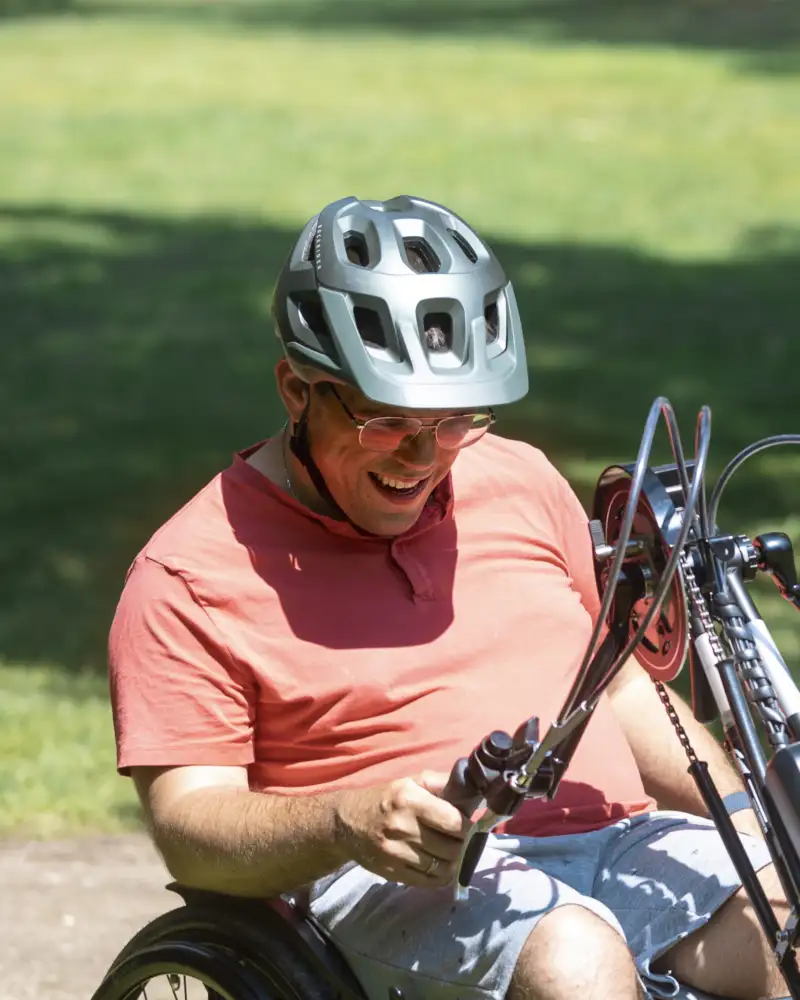 Ein Mann mit Fahrradhelm sitzt in einem Rollstuhlrad mit Elektromotor.