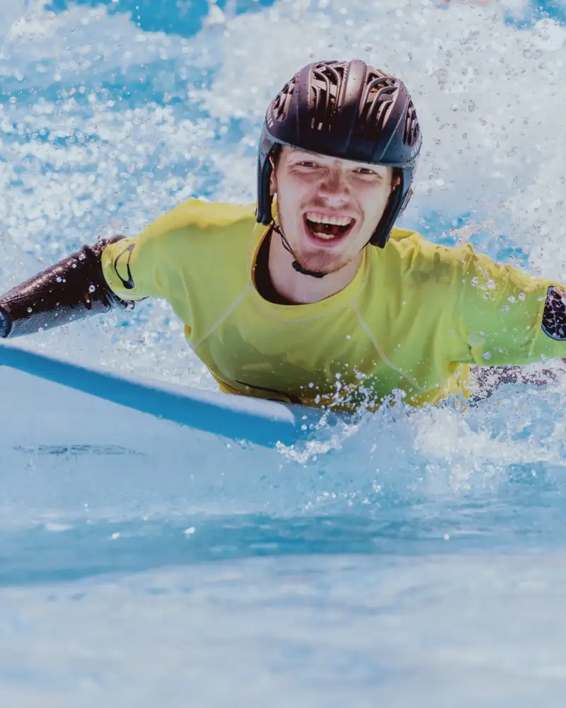 Ein Teilnehmer des inklusiven Surf-Projektes kann bereits allein auf seinem Surfboard die Wellen reiten und hat großen Spaß dabei.